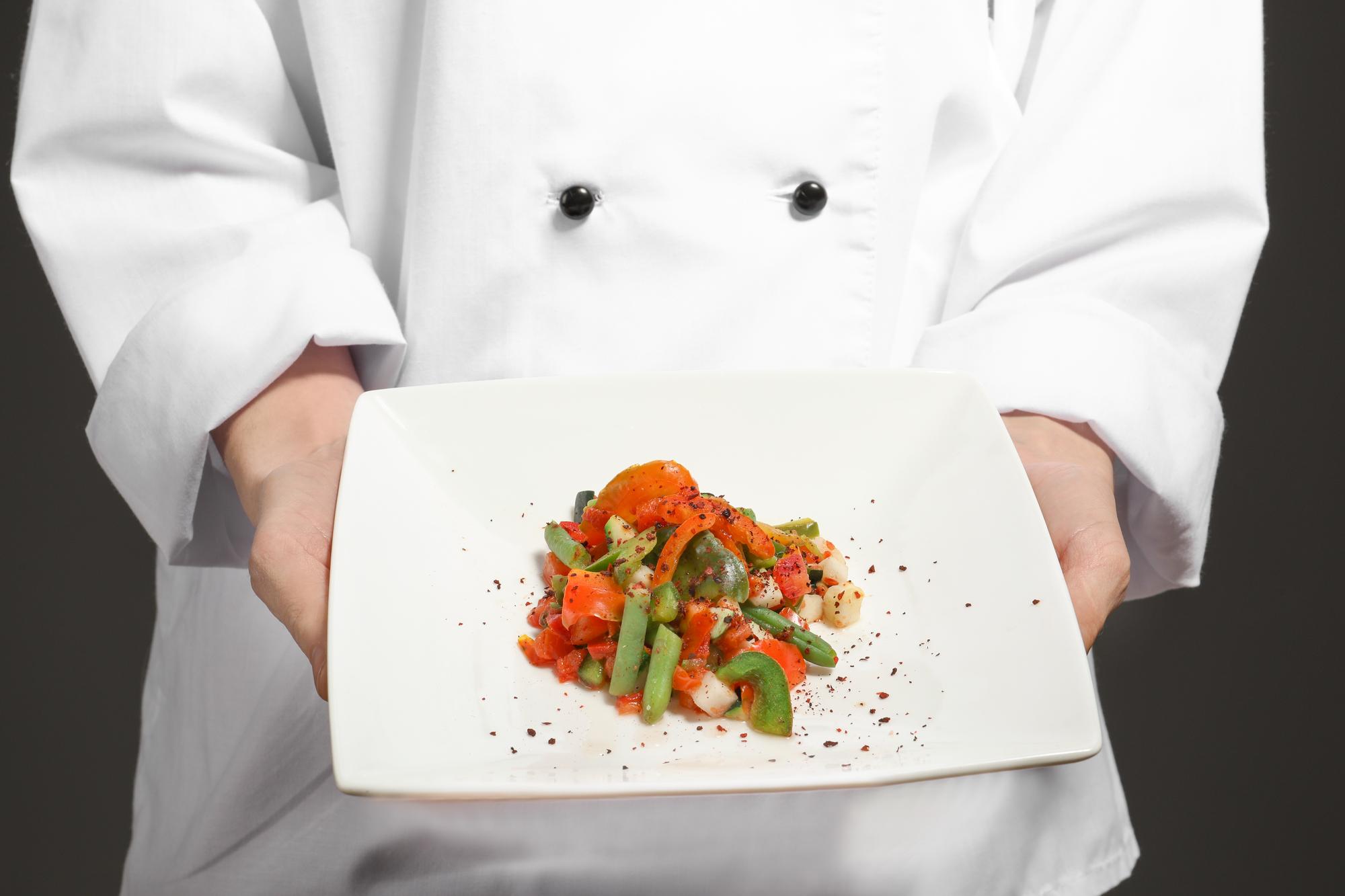 Chef arranging plated dish in studio kitchen